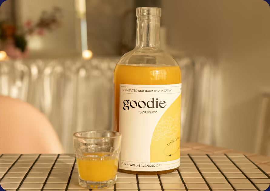 A bottle of Goodie Sea Buckthorn and a glass on a table